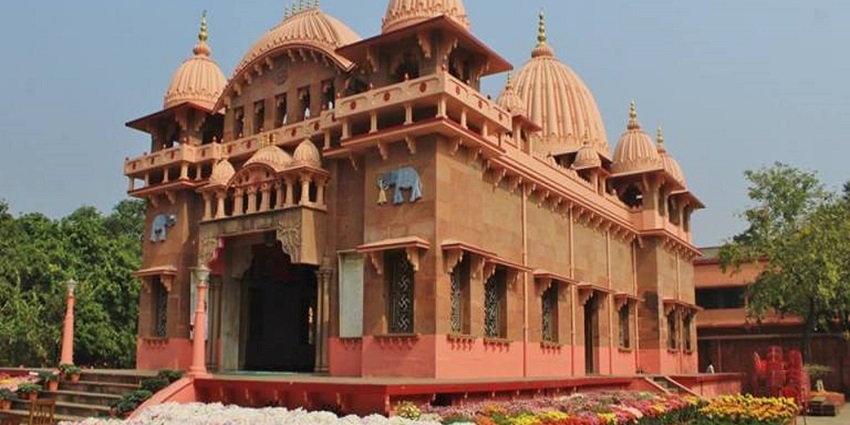 Rust‑red temple building at Sri Ramakrishna Ashrama, Nimpith, with domes and columns.