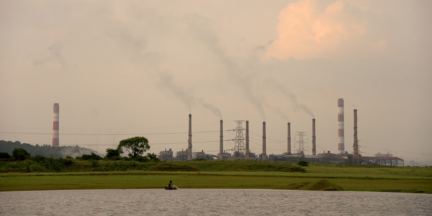 A view of Rihand Dam with water streaming over its massive structure and greenery.