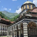 Rila monastery entrance with detailed architecture and people entering the monastery.