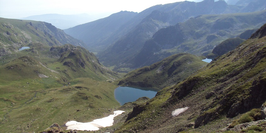 Rila National Park with multiple lakes, surrounded by green mountains and a little snow.