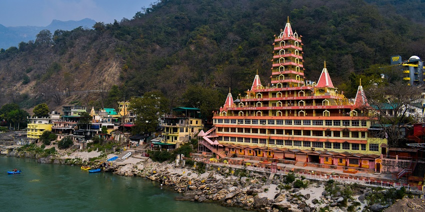 A tall building along the riverbank - one of the best places to visit in Uttarakhand in April