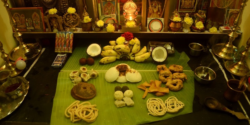 Hindu ritual of offering food to gods on a banana leaf with brass altars and flowers