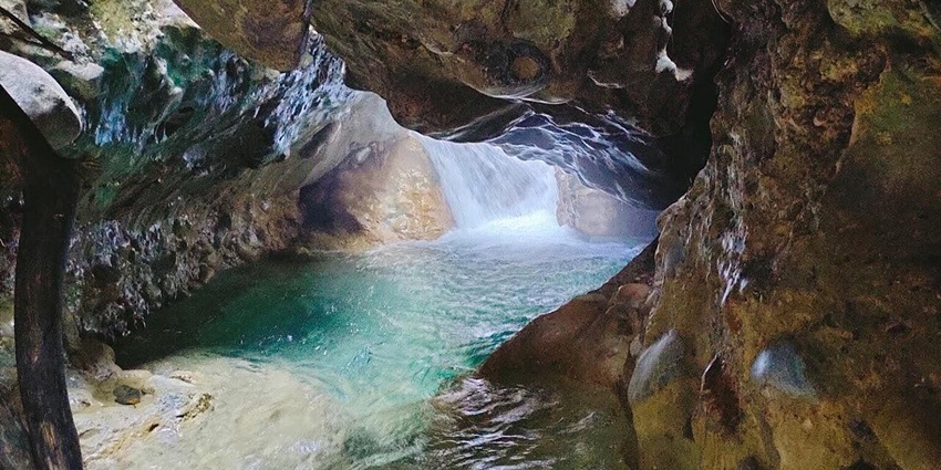 Scenic cave formation with a crystal clear river flowing through it