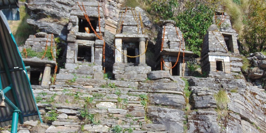Places to visit in Rudraprayag feature a temple surrounded by mountains and lush greenery.