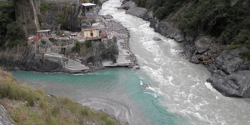 A view of Rudraprayag in Uttarakhand, India, showing green hills and a winding river.