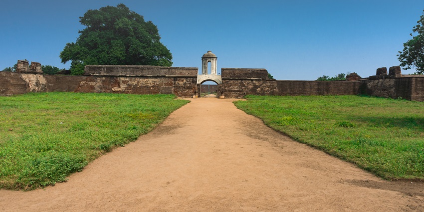 An empty field filled with grass on either side of the ground and a fort in the front.