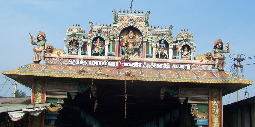 A view of the entrance of Samayapuram Mariamman Temple with colourful gopuram and devotees.