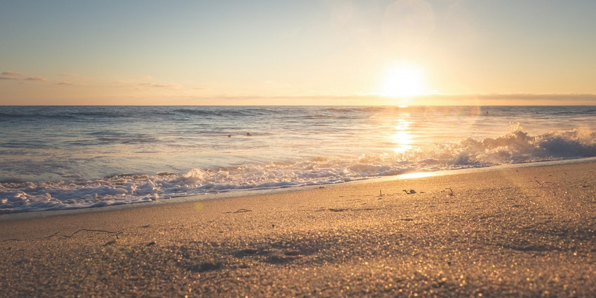 The sun rising behind the sandy shores and gentle waves of the Samiyar Pettai Beach.