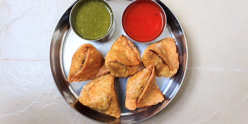 Samosa known as an Indian street food in Nagpur that is served with sweet ketchup and spicy chilly sauce