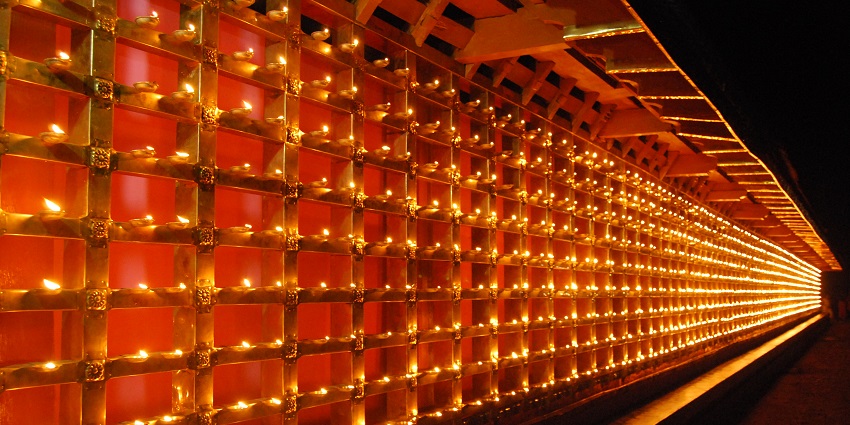 Hundreds of burning diyas lined up in the temple walls