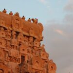 Tall and intricately carved Gopuram of Brihadisvara Temple against pink-blue sky