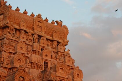 Tall and intricately carved Gopuram of Brihadisvara Temple against pink-blue sky