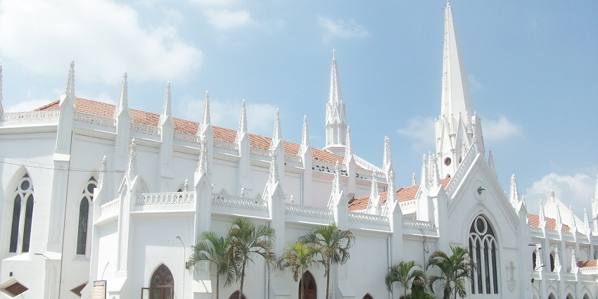 White Santhome church in Gothic cathedral architecture with trees near the gates.