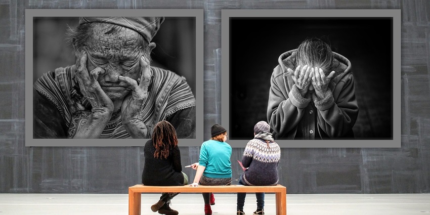 A picture of women sitting on a bench and admiring the art pieces placed on the wall in front of her