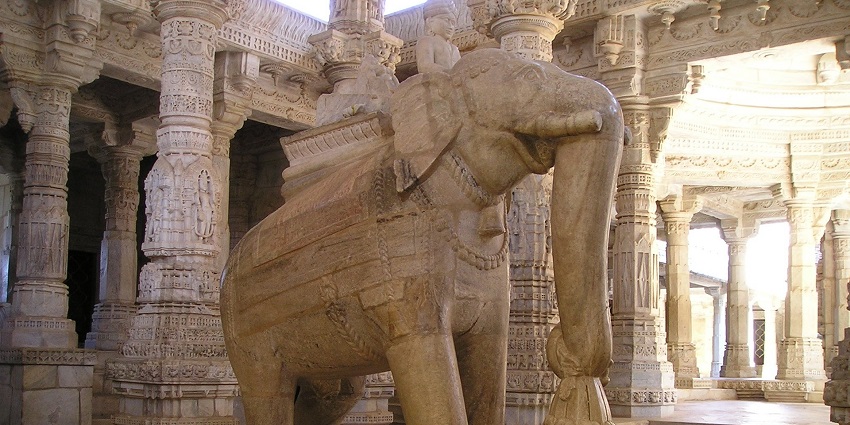 Temple entrance in India with intricate carvings and an elephant statue in front.