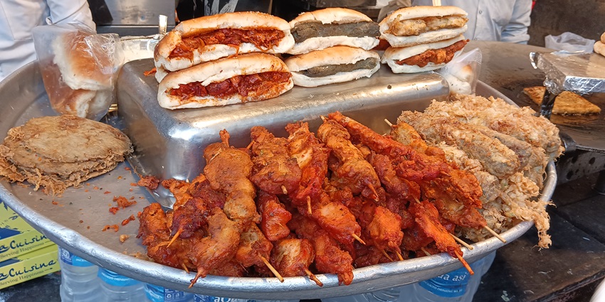 A view of street food in Colaba with locals gathered around food stalls serving kebabs, chaat, and other delicacies.