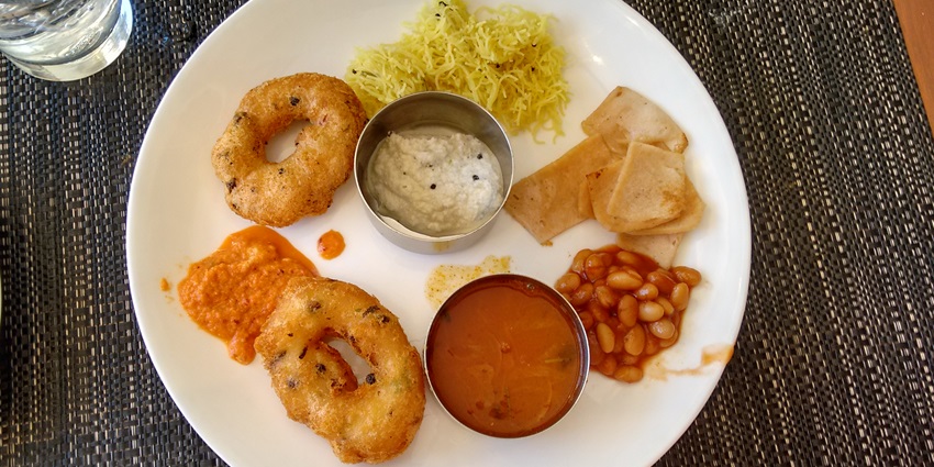 An image of a white plate with the delicious traditional south indian meal served on it.