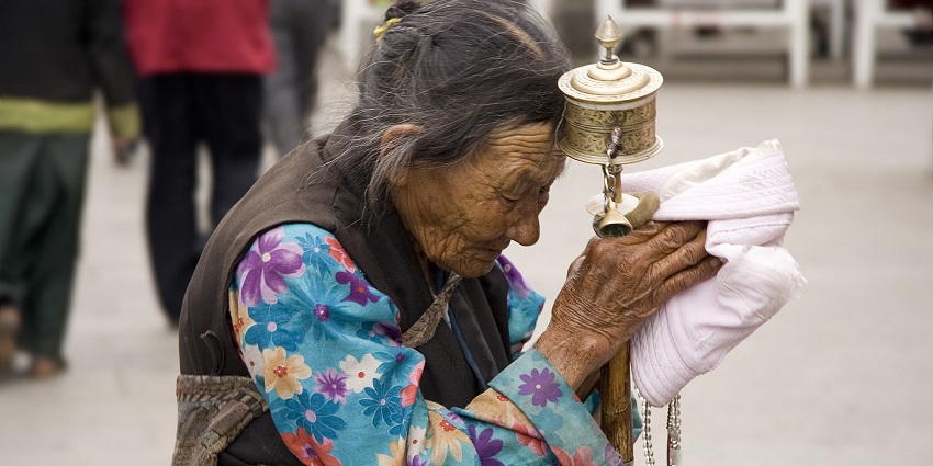 An elderly woman with closed eyes appears to be in a state of devotion and prayer.