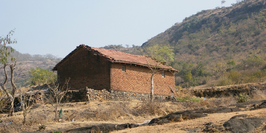 A serene view of the Semmedu Village, featuring houses made of mud and trees.