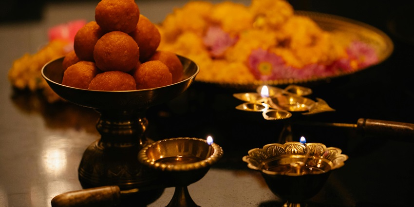 Lighted diyas and prashad, along with flowers, all the elements of worship being kept together.