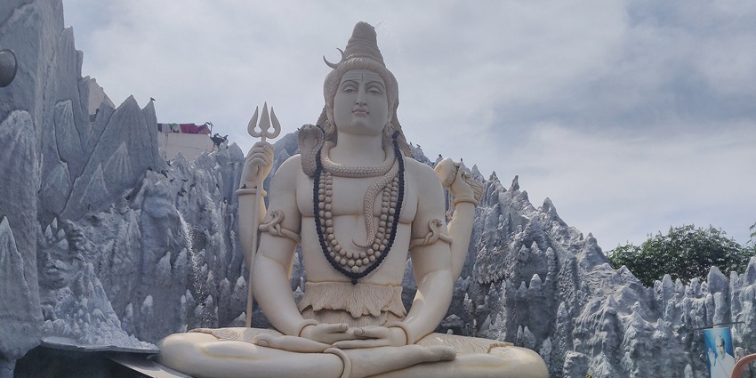 A beautifully ornate Lord Shiva temple, showcasing intricate architectural details and surrounded by lush greenery.