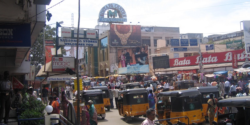 A picture of the bustling road of Chennai, filled with vehicles and stalls.