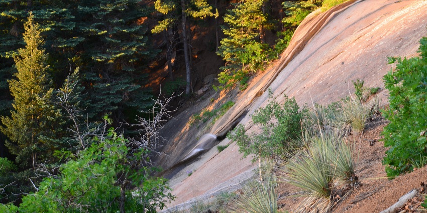 Silver Cascade Waterfall flowing over rocky cliffs in a thick green forest