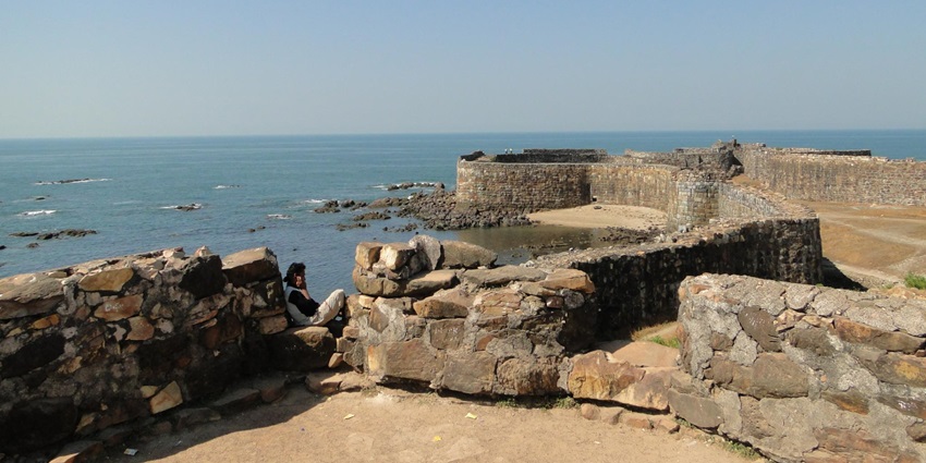 A picture of the exterior wall of the historical Sindhudurg Fort with views of the city in the background