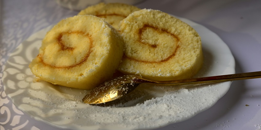 An image of two slices of a spiral sweet dish on a white plate, similar to Singhal
