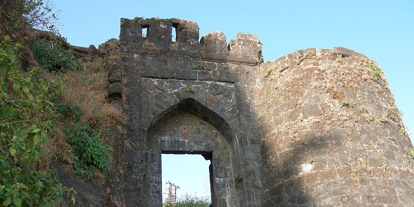 Entrance of Sinhagad fort, surrounded by lush shrubs and moss