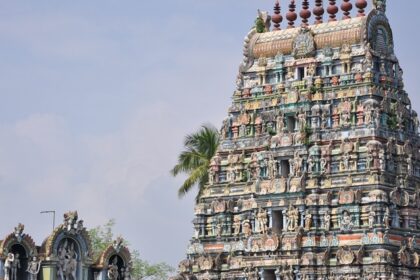 A distant view of a South Indian temple whose outer structure has intricate carvings.