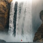 An image showing a beautiful waterfall cascading down a tall cliff, creating a pond.