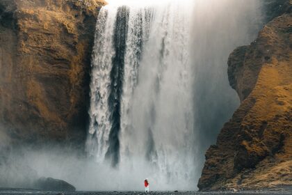 An image showing a beautiful waterfall cascading down a tall cliff, creating a pond.