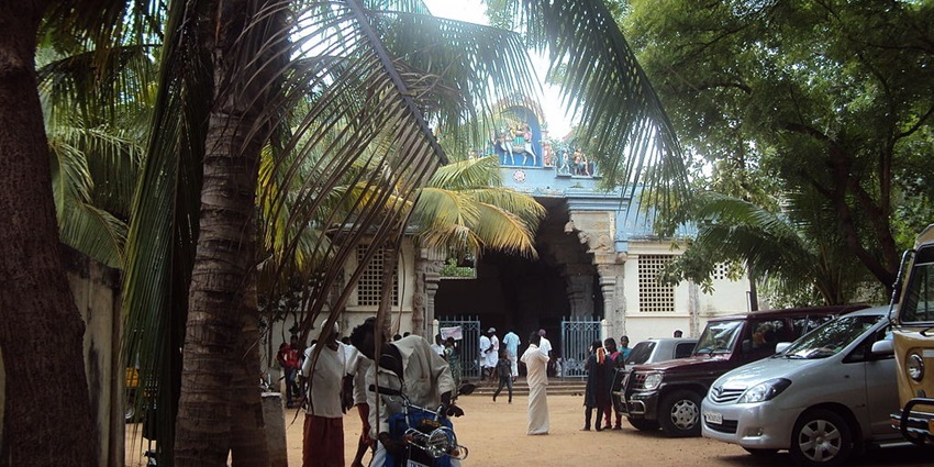 Cars parked outside of Sivasailam temple with people walking and surrounded by greenery