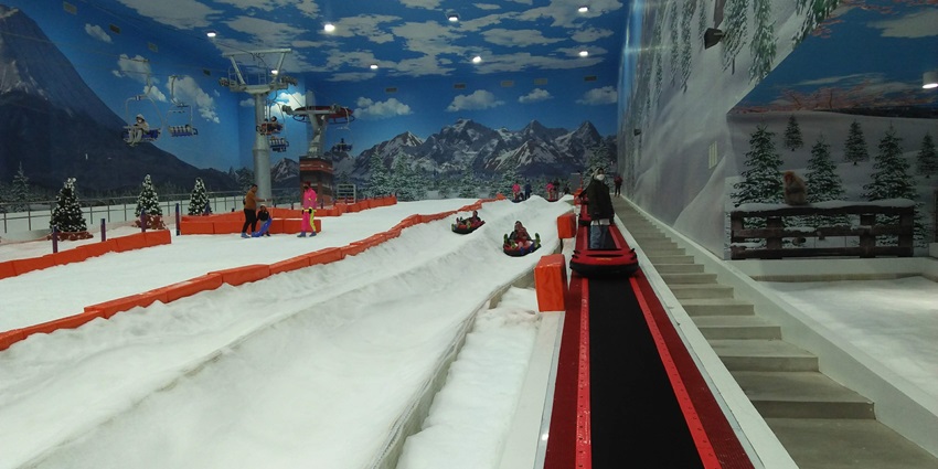 An image of families enjoying skiing and snow activities at an indoor snow park.