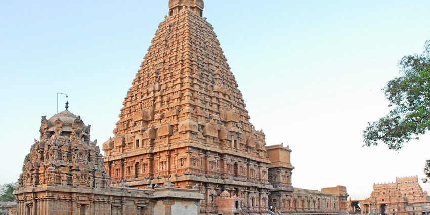 A distant view of an ancient temple which is humongous is being admired by people.