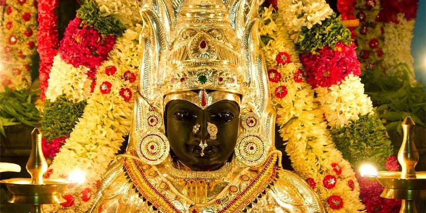 Sri Angala Parameshvari Temple with parked buses and people in an open sandy area