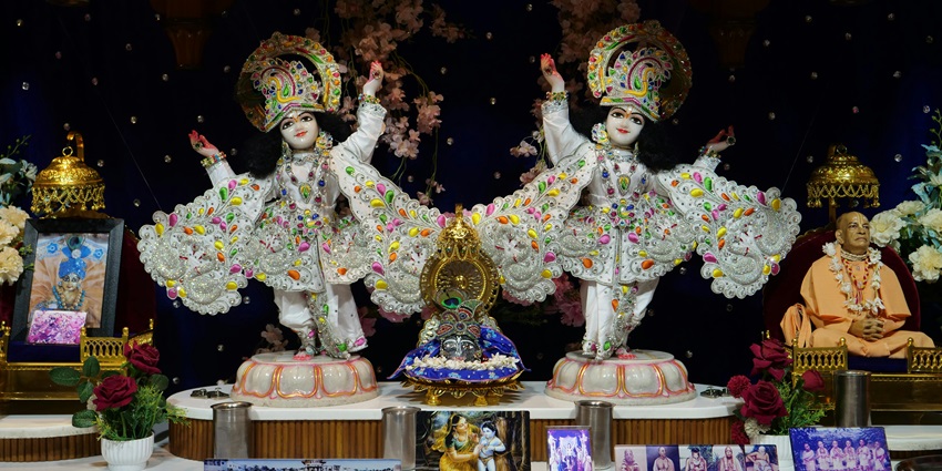 Krishna figures displayed on an altar, surrounded by colorful decorations for worship
