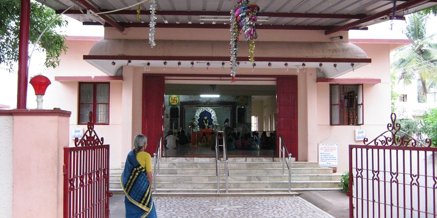 An old lady is standing in front of the sanctum and rituals are taking place inside it