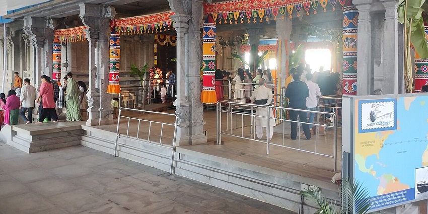 Grand ISKCON temple with intricate carvings, vibrant domes, and devotees engaging