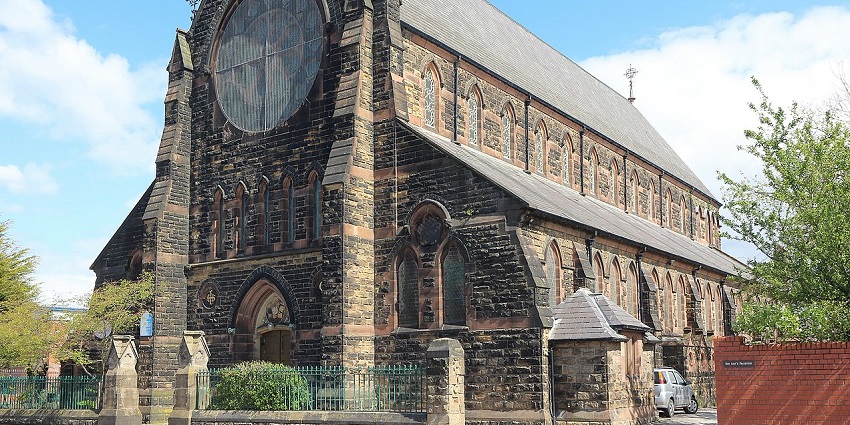 Gothic-style church with ornate spires, colorful roof tiles, and detailed facade under a blue sky