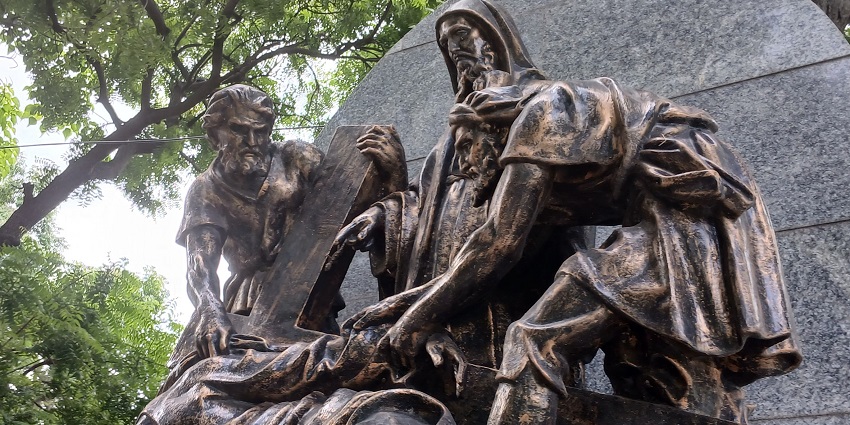 A picture of a sculpture in a park built with marbles, surrounded by lush greenery