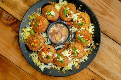 A glimpse of pani puri beautifully decorated and served on a black plate on a table.