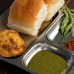 A combination of Maharashtrian food is served on a plate with other accompaniments.