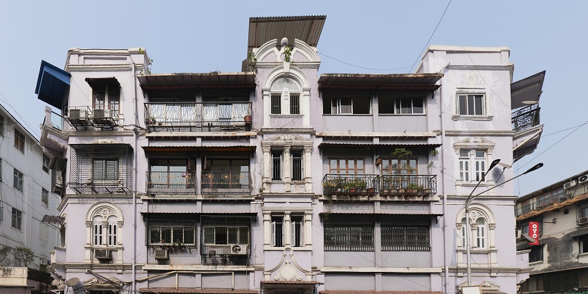 A building in a bustling street market in Colaba Causeway, Mumbai, showcasing local shops and vendors.