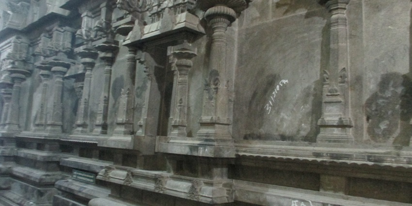 Close-up of the grey walls of Alangudi Temple, featuring traditional stone pillars.