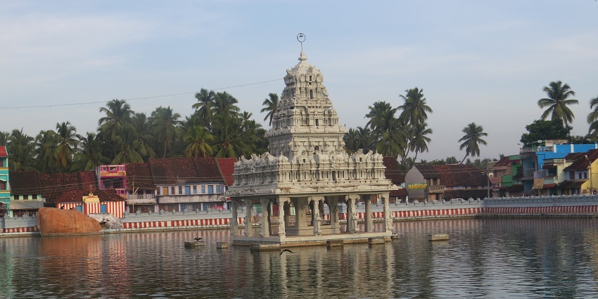 A panoramic view of the ancient Suchindram Temple surrounded by water in a holy tank.