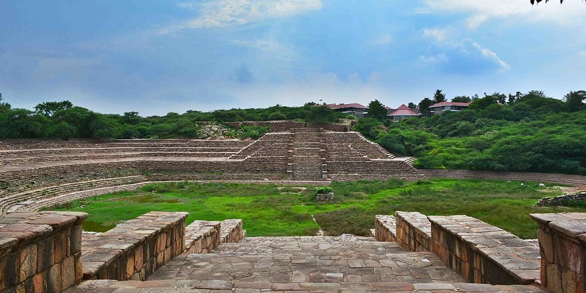 Historic Suraj Kund structure with stone masonry steps and arches, surrounded by natural greenery