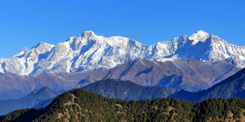 Kedarnath and Kedar Dome peaks in Uttarakhand, covered in snow under a clear sky.