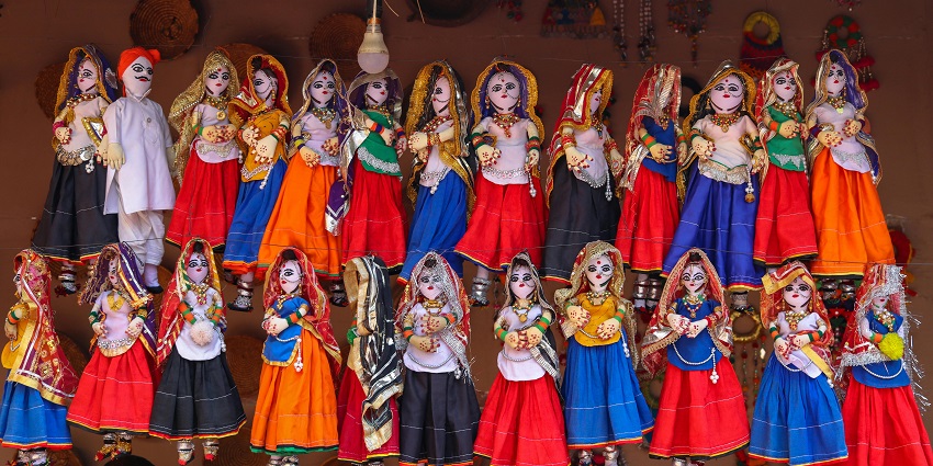 A display of dolls hanging from a wall representing the vibrant festive of the region.
